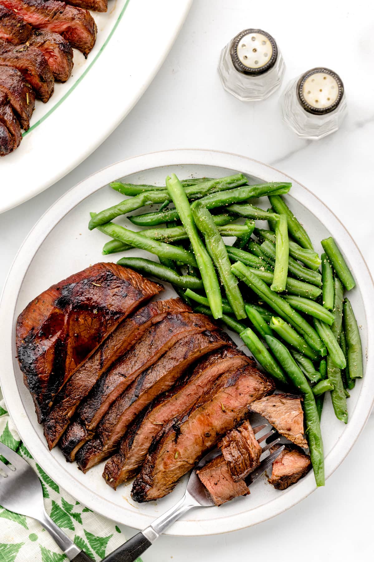 A sliced flat iron steak recipe served with green beans.
