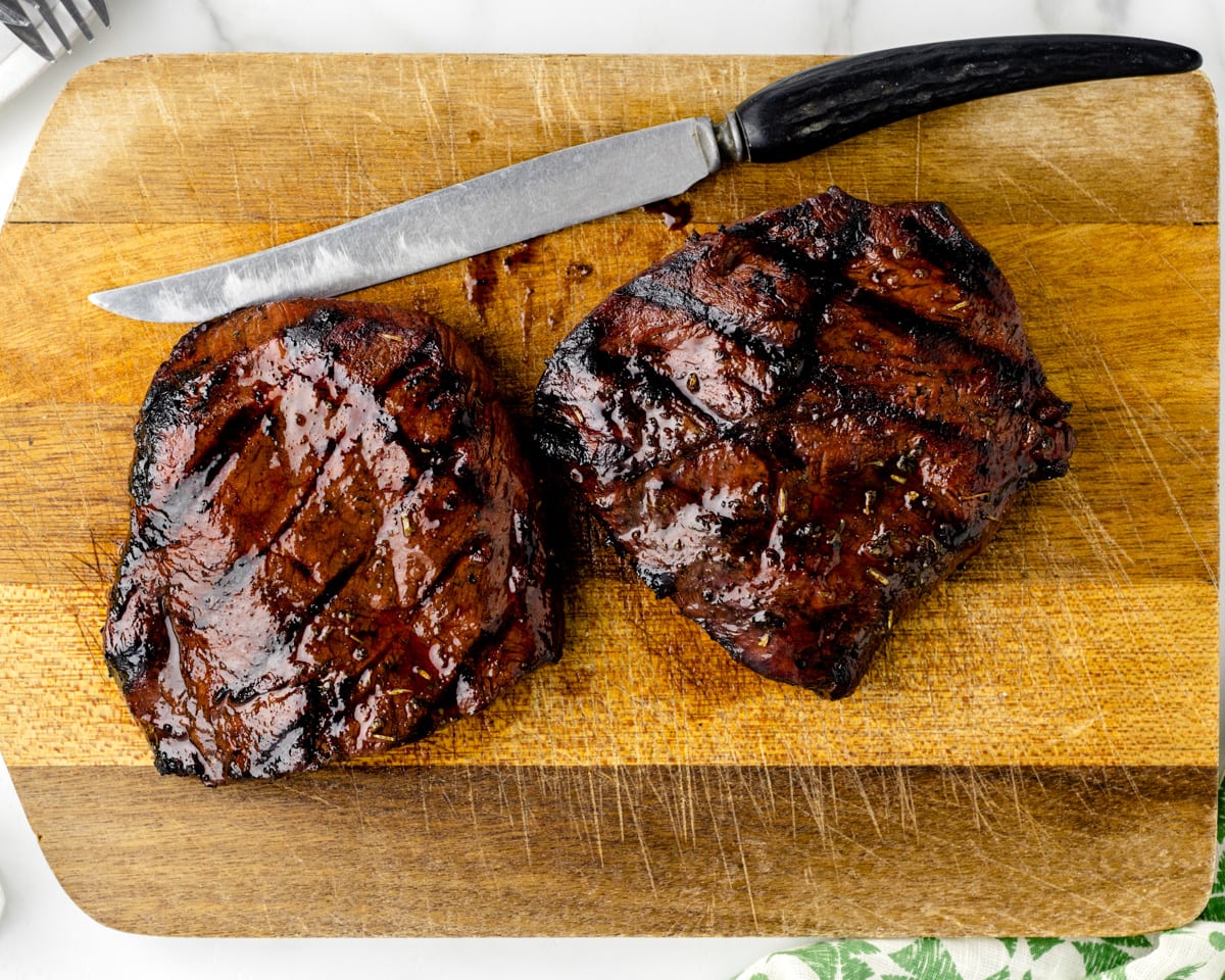 A grilled steak resting on a cutting board.