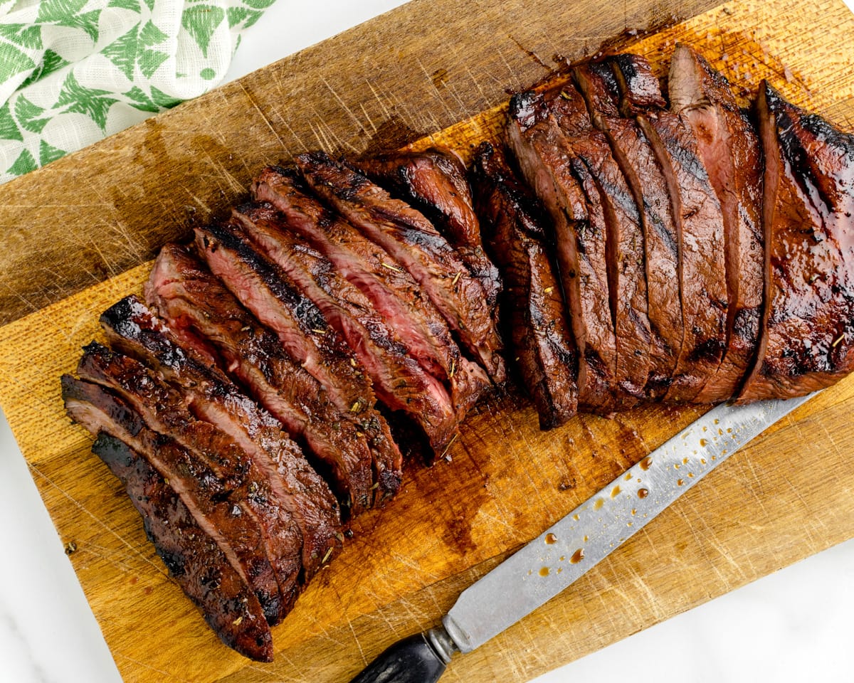 A grilled steak sliced on a cutting board.