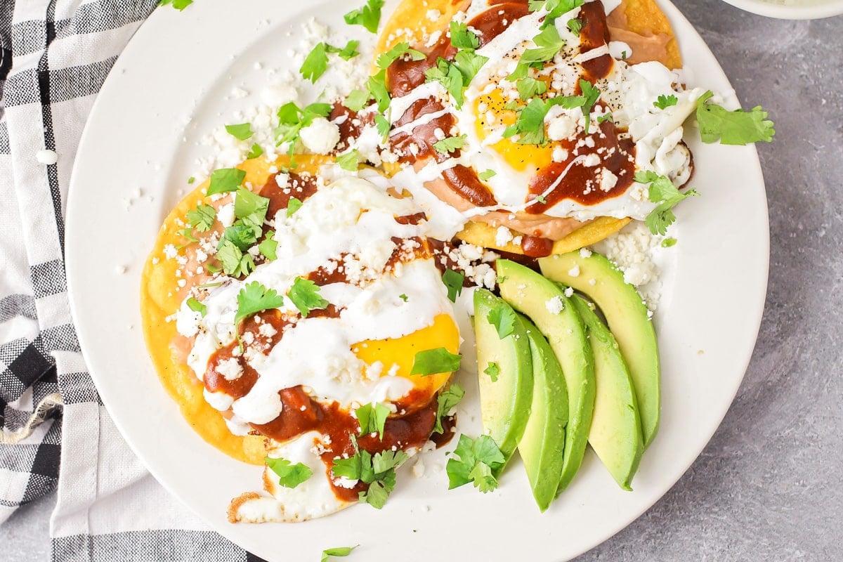 A plate of huevos rancheros topped with cilantro, crema, and cotija cheese.