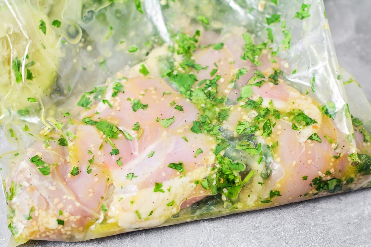 Chicken and cilantro marinade in a ziploc bag.