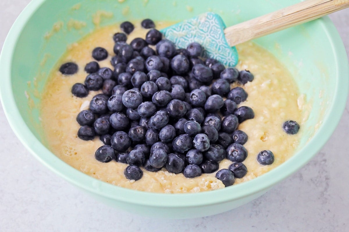 Adding blueberries to a bowl of batter.