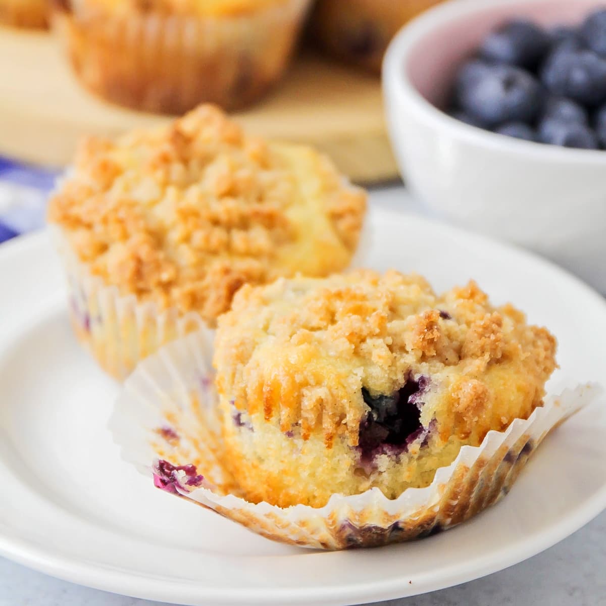 Two lemon blueberry muffins on a white plate.