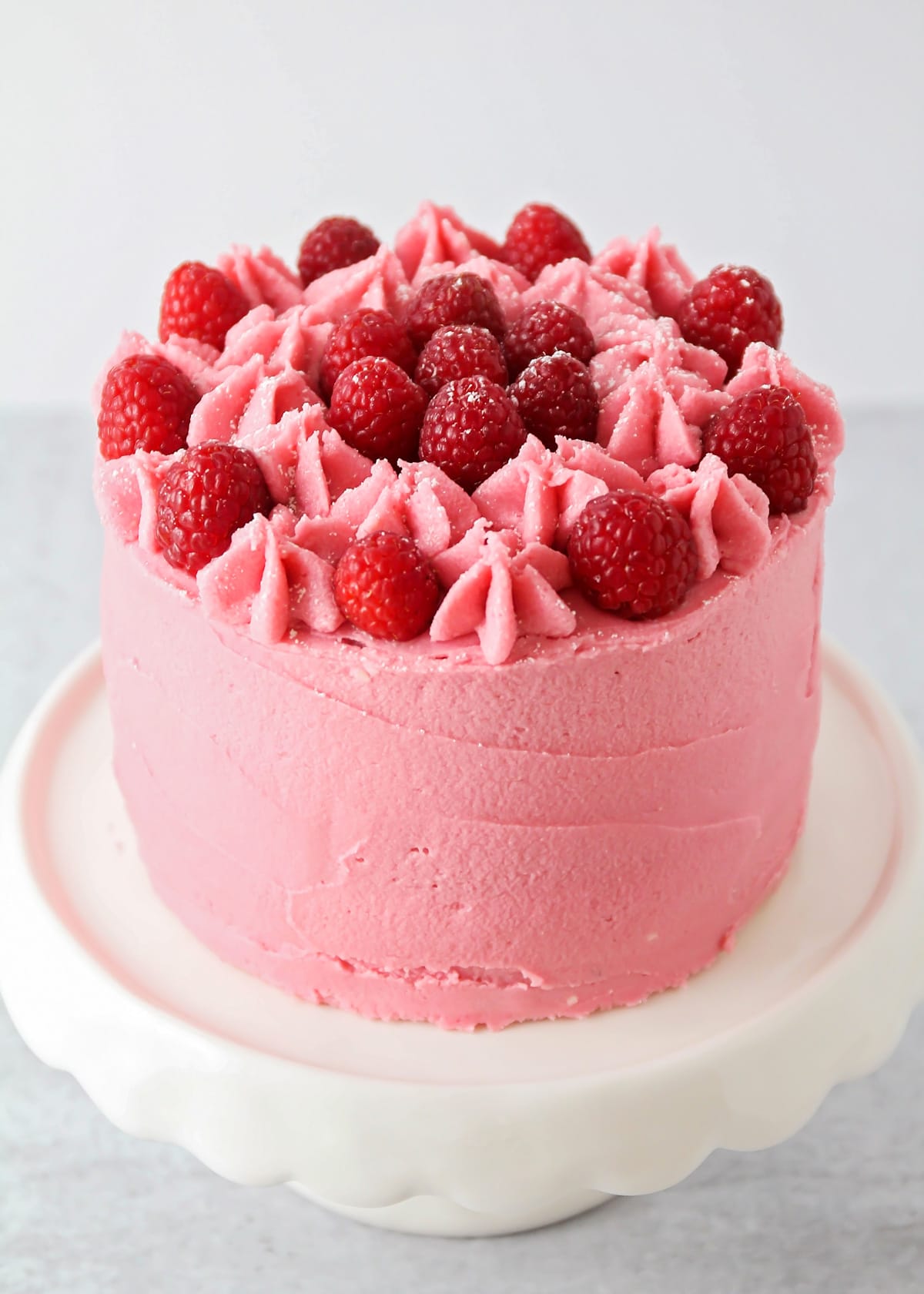 Lemon raspberry cake served on a white cake stand.