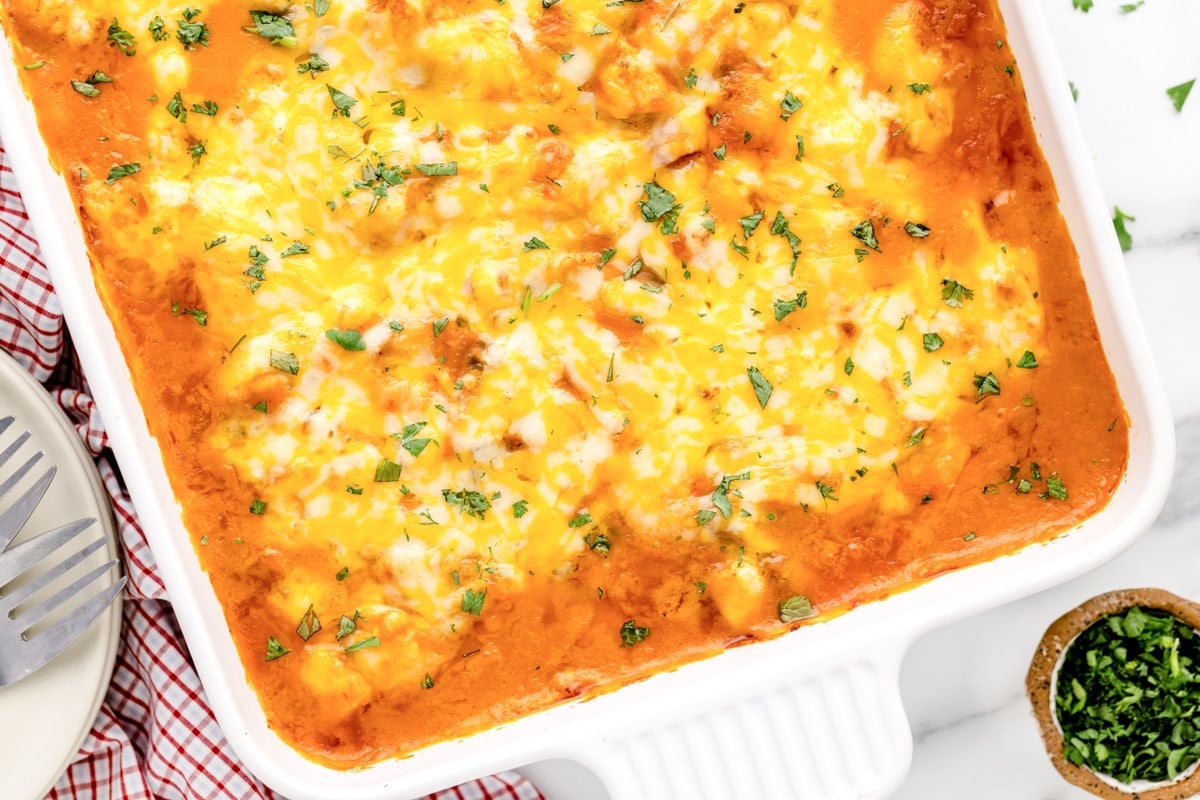 Close up of a cheesy casserole baked in a white casserole dish.