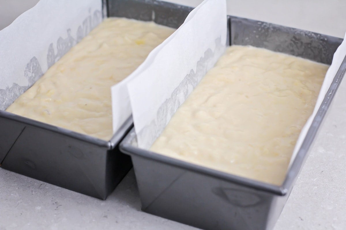 Two lined loaf pans filled with bread batter.