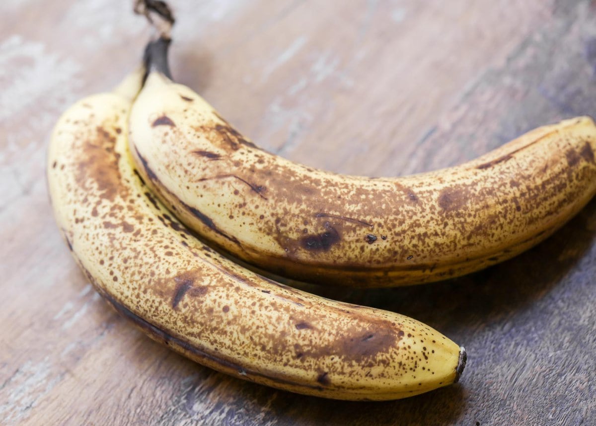 Two ripe bananas sitting on a wooden table.