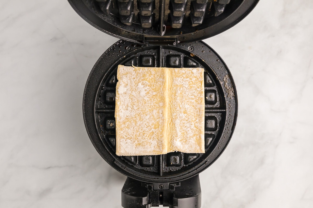 Placing puff pastry on a waffle iron.