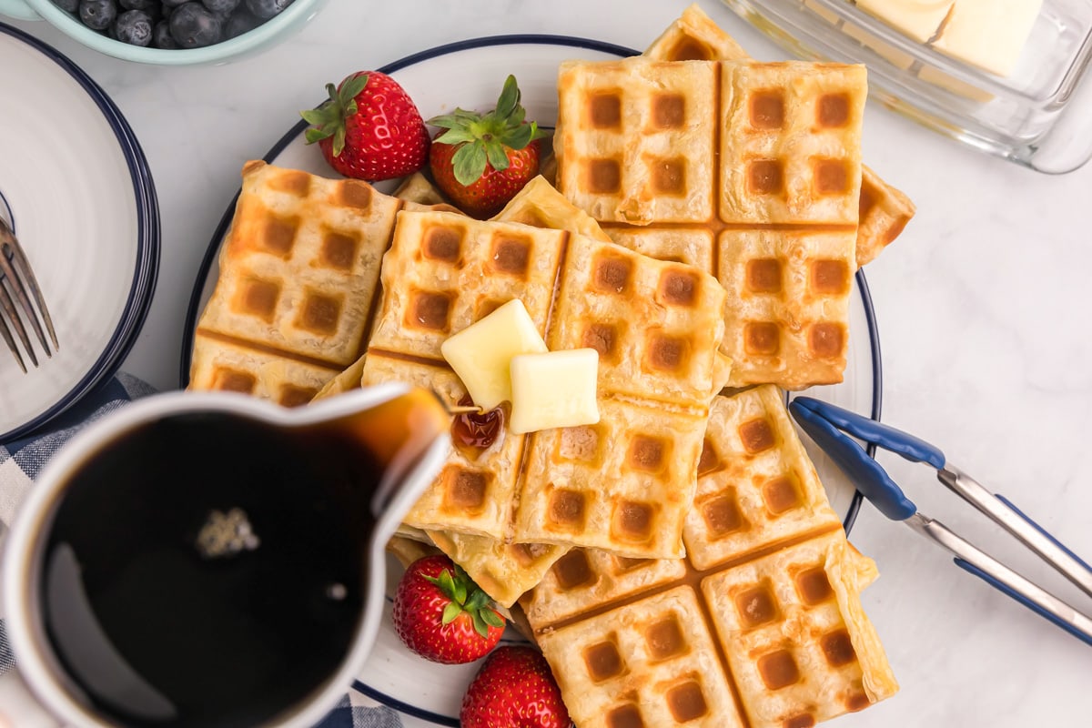 Waffles topped with butter and maple syrup.