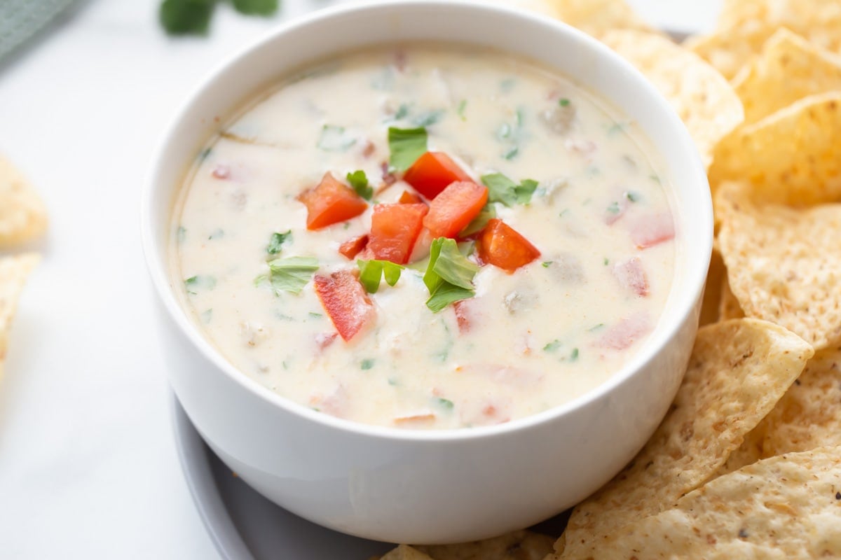 A white bowl filled with queso blanco and topped with diced tomato.