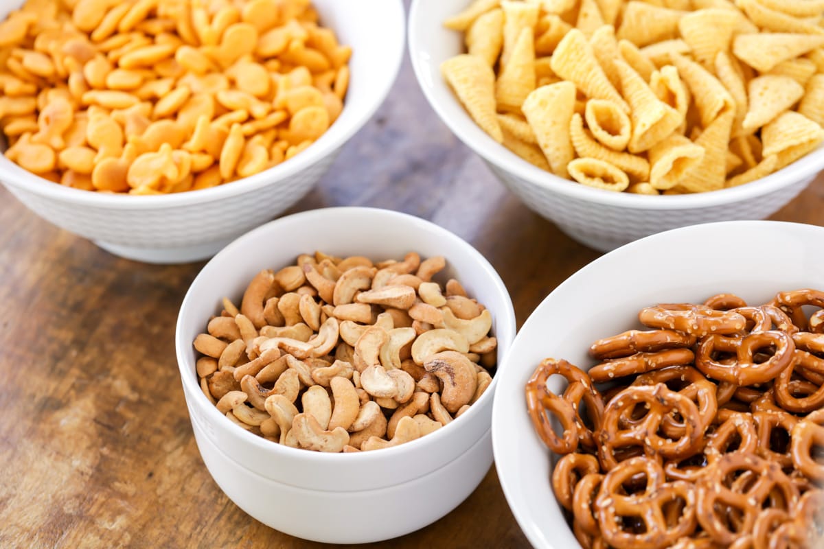 Bowls of Bugles, pretzels, goldfish, and cashews on a kitchen table.