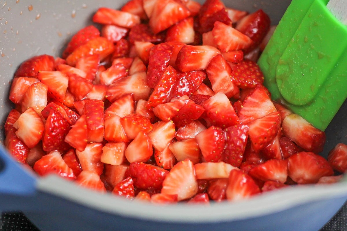 Mixing chopped fruit with sugar.