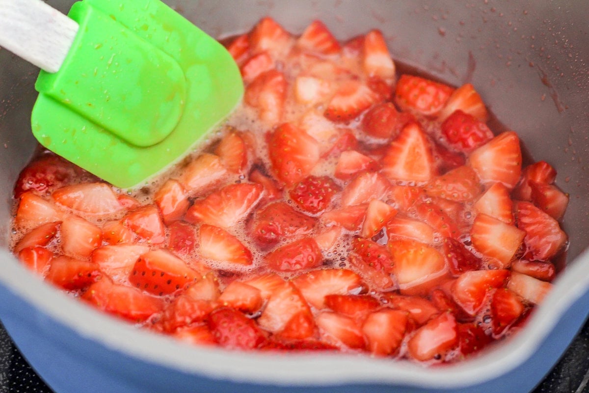 Chopped strawberries in liquid in a gray pot.