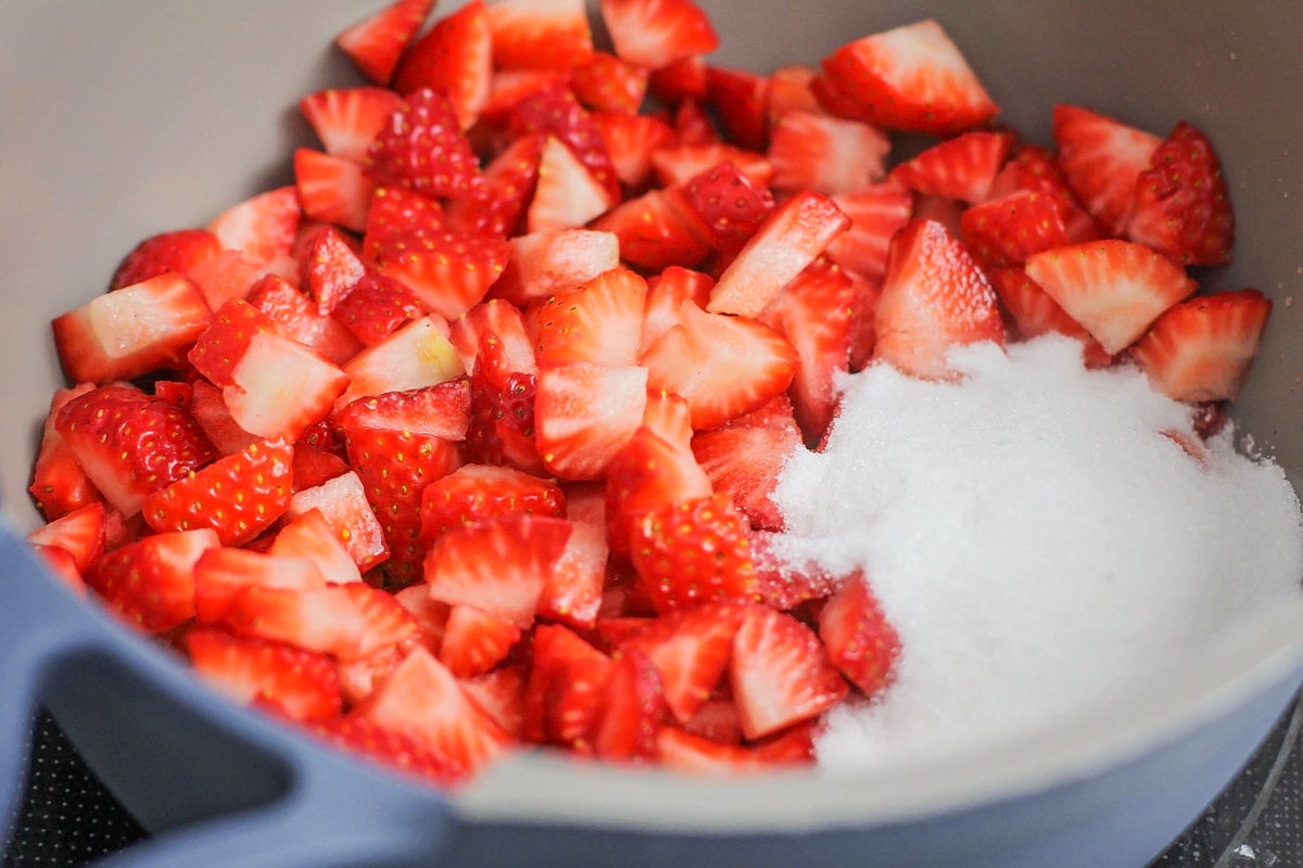 Chopped strawberries and sugar in a gray pot.