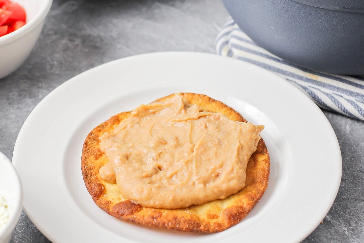 Creamy beans spread on top of fried corn tortilla.