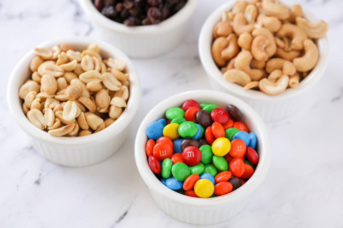White bowls filled with m&ms, nuts, and chocolate chips.