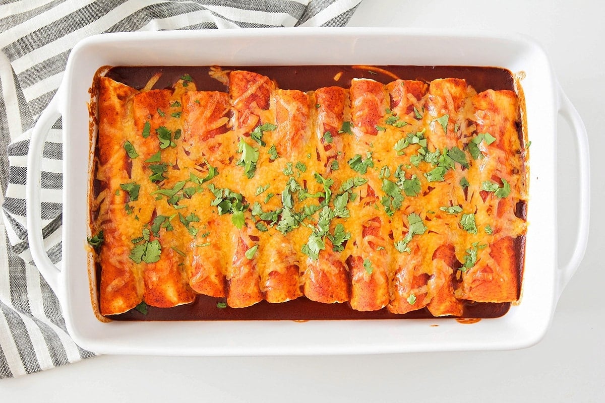 A pan full of beef enchiladas topped with cheese.