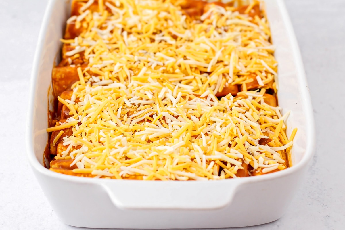 Cheese enchiladas rolled up in baking dish.