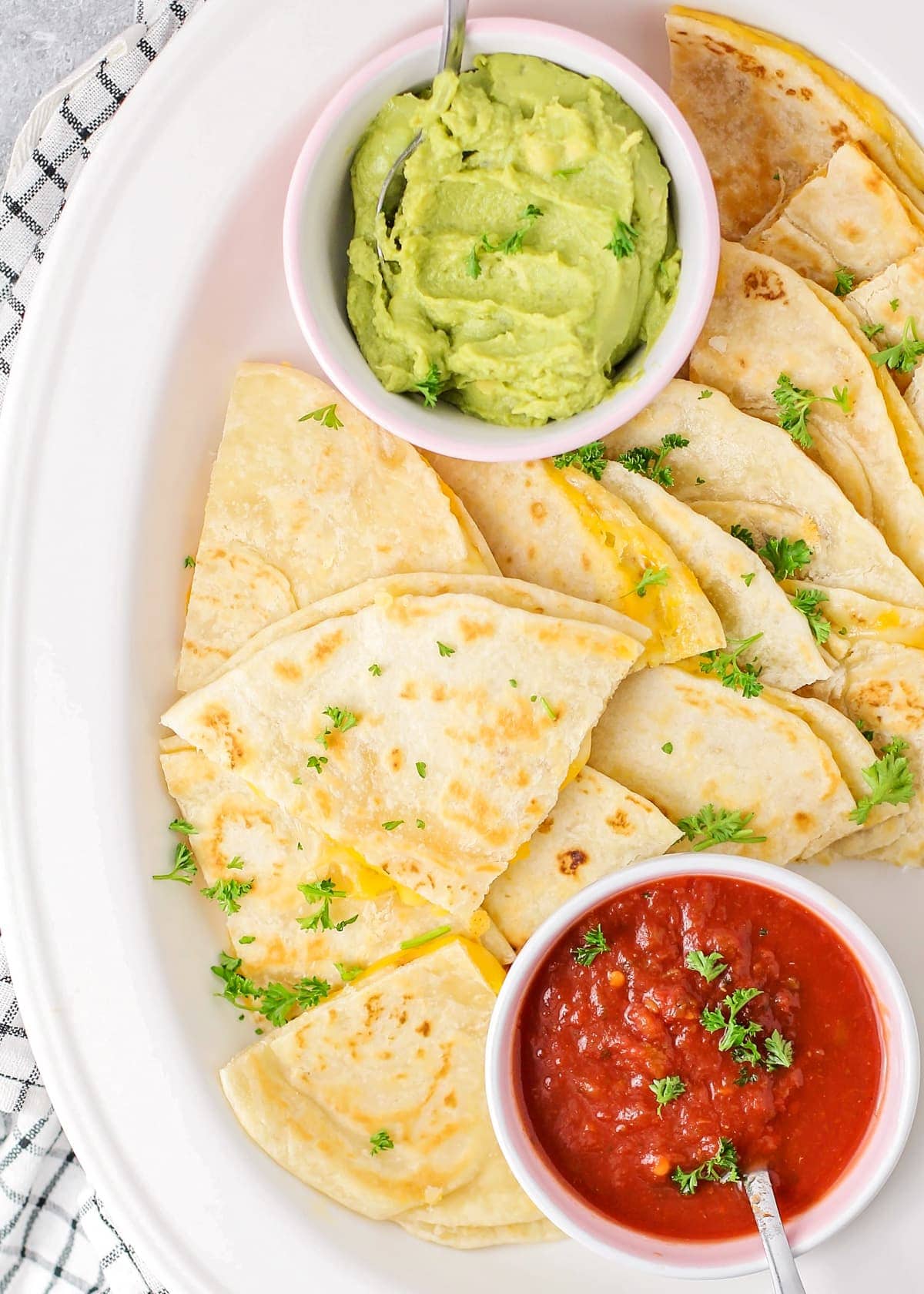 A platter filled with cheese quesadilla, salsa, and guacamole.