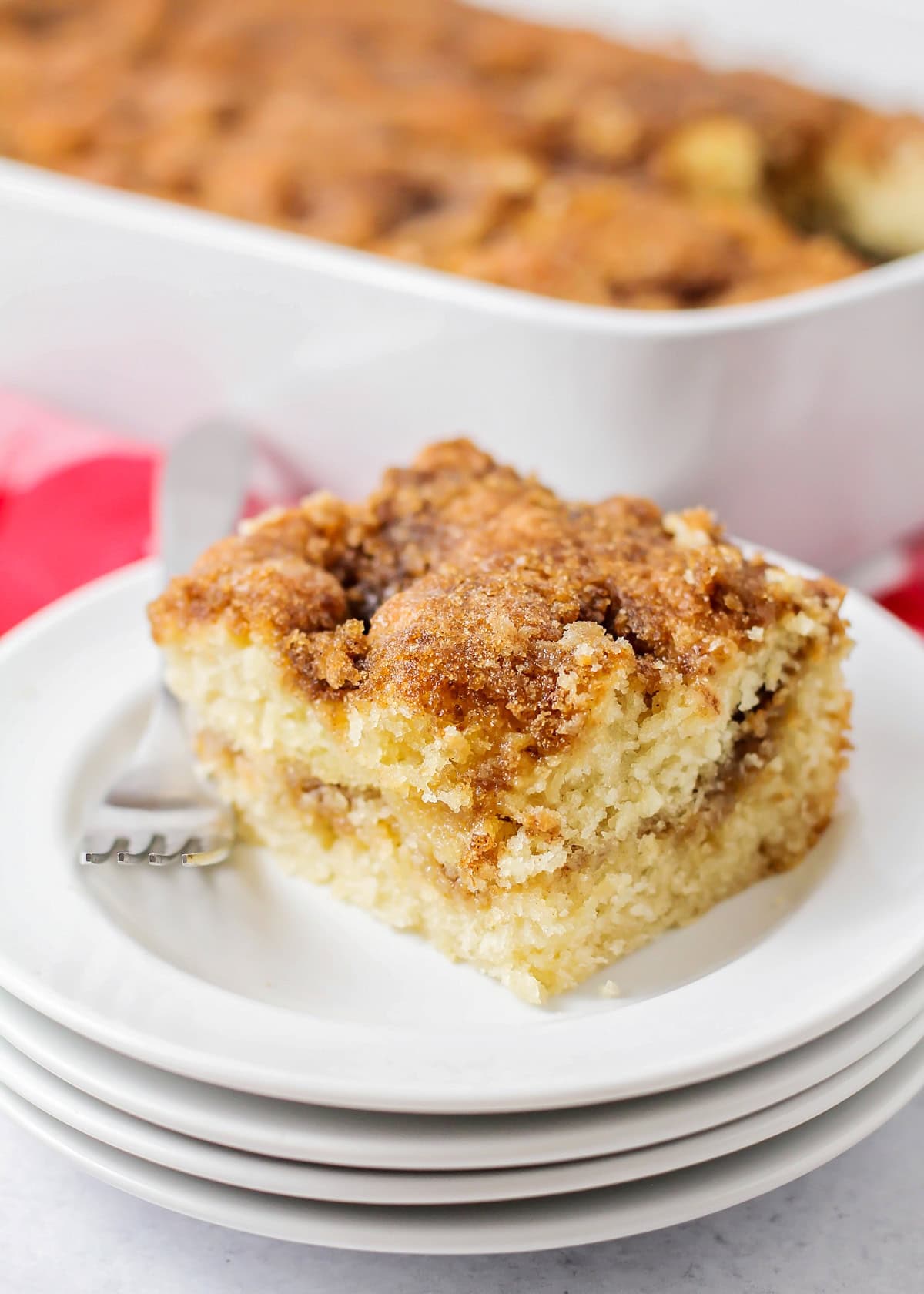 Coffee cake recipe slice on stack of white plates with fork.