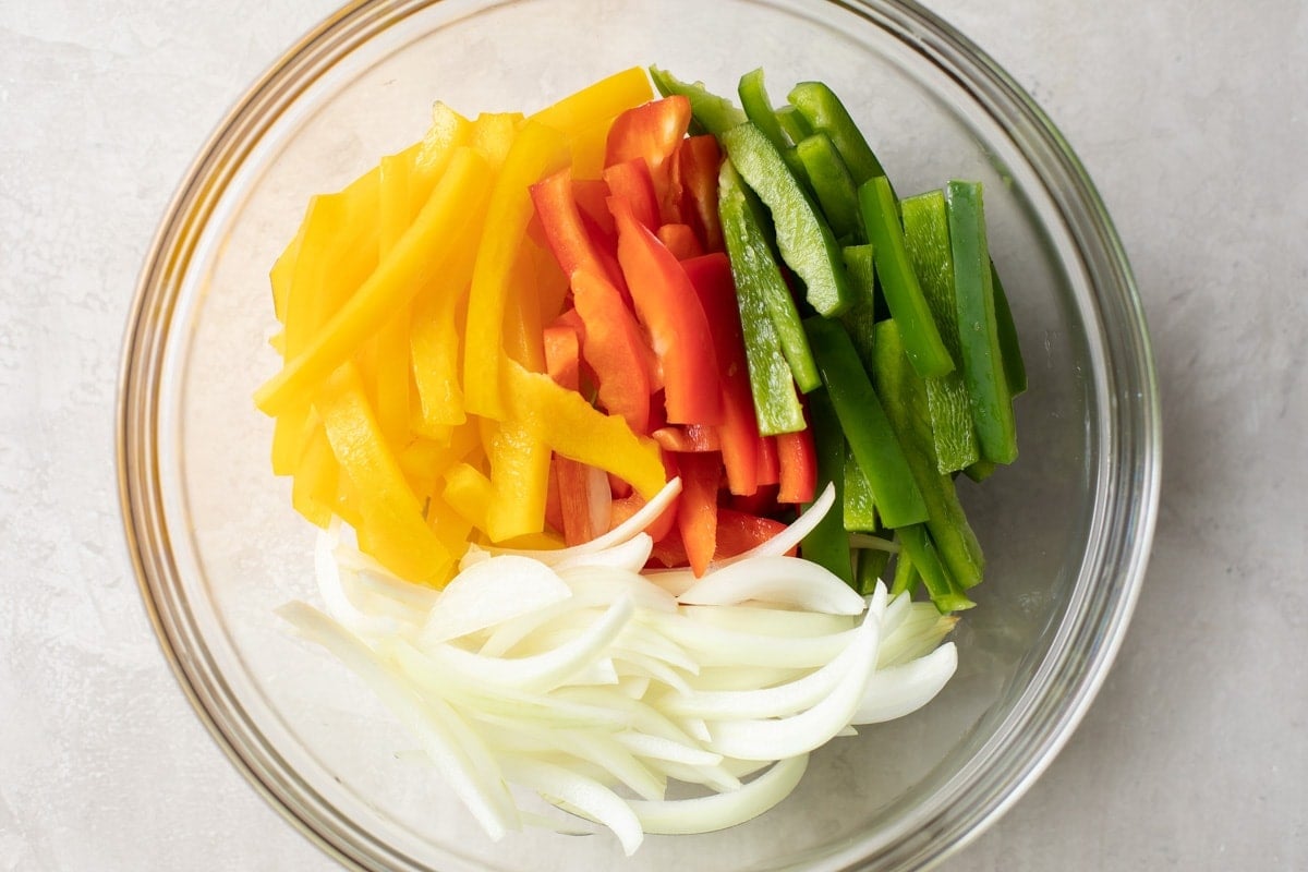 Sliced veggies in a glass bowl on a kitchen counter.