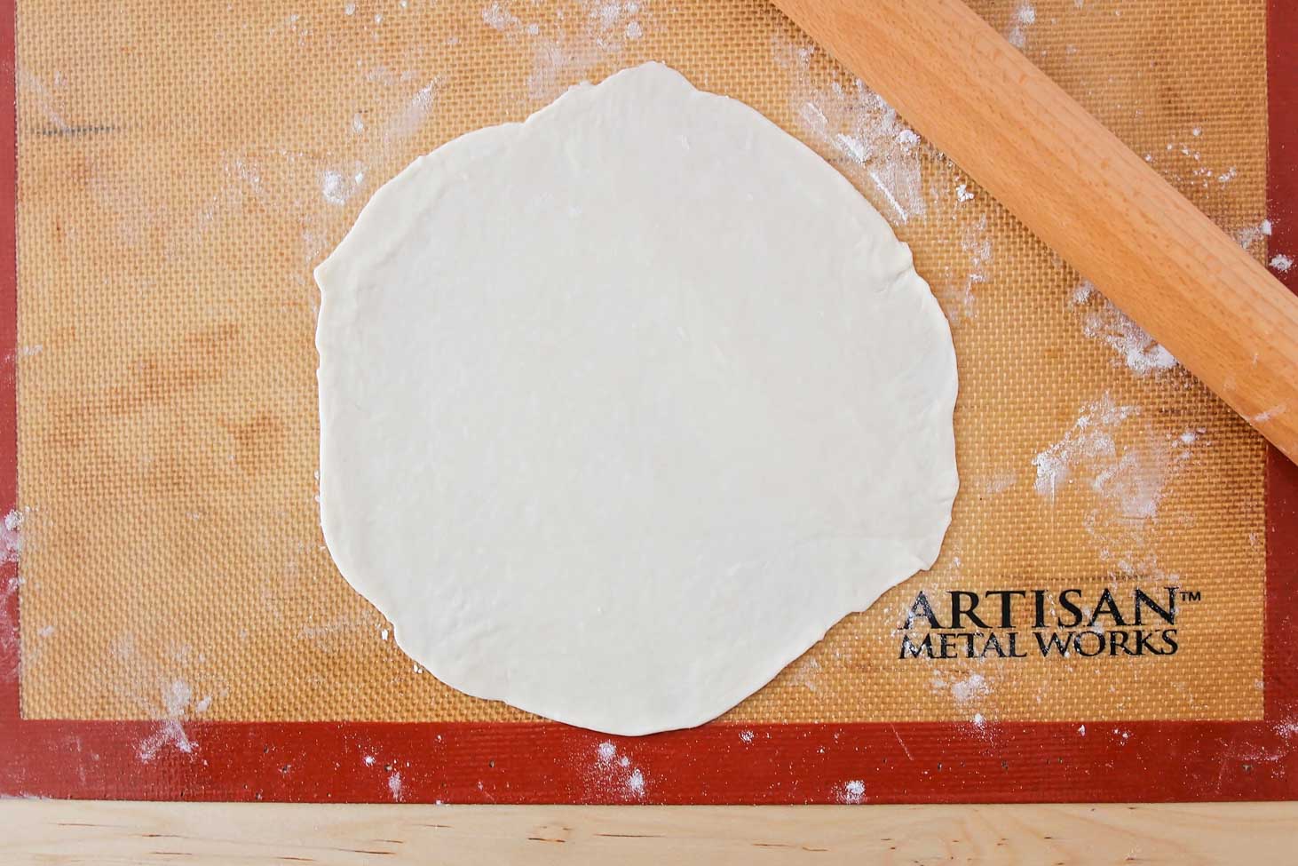 Flour tortilla dough rolled out on a mat.