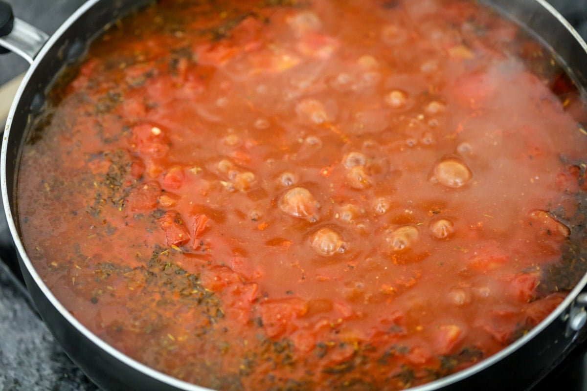 Tomato sauce boiling in a skillet on the stove.