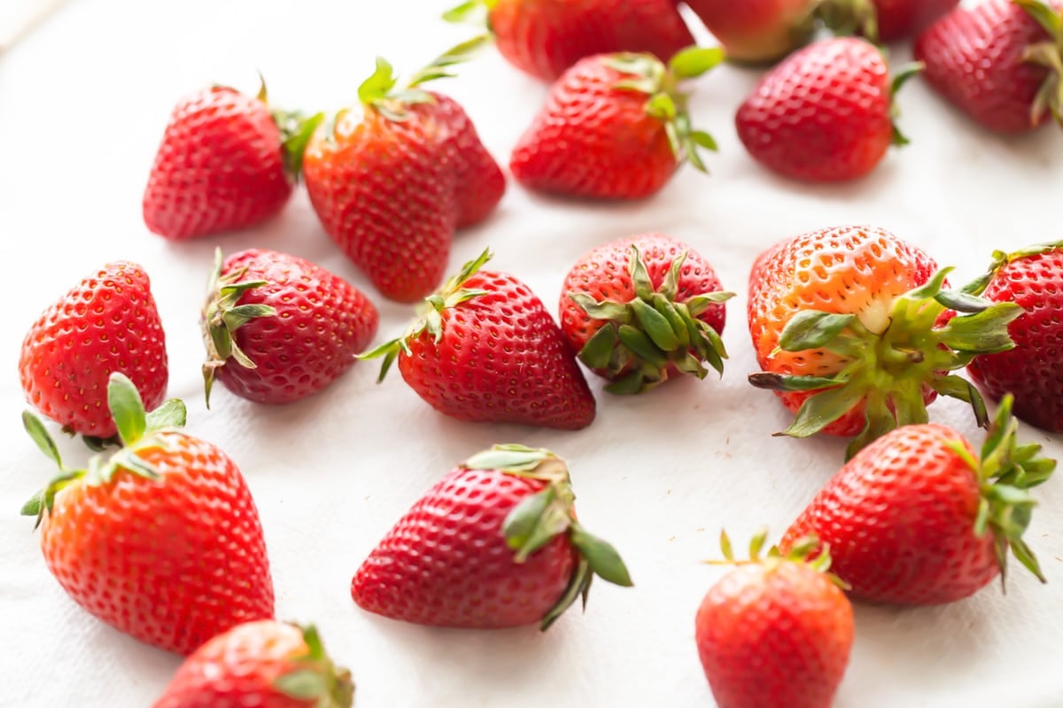 Strawberries laying out on paper towels.