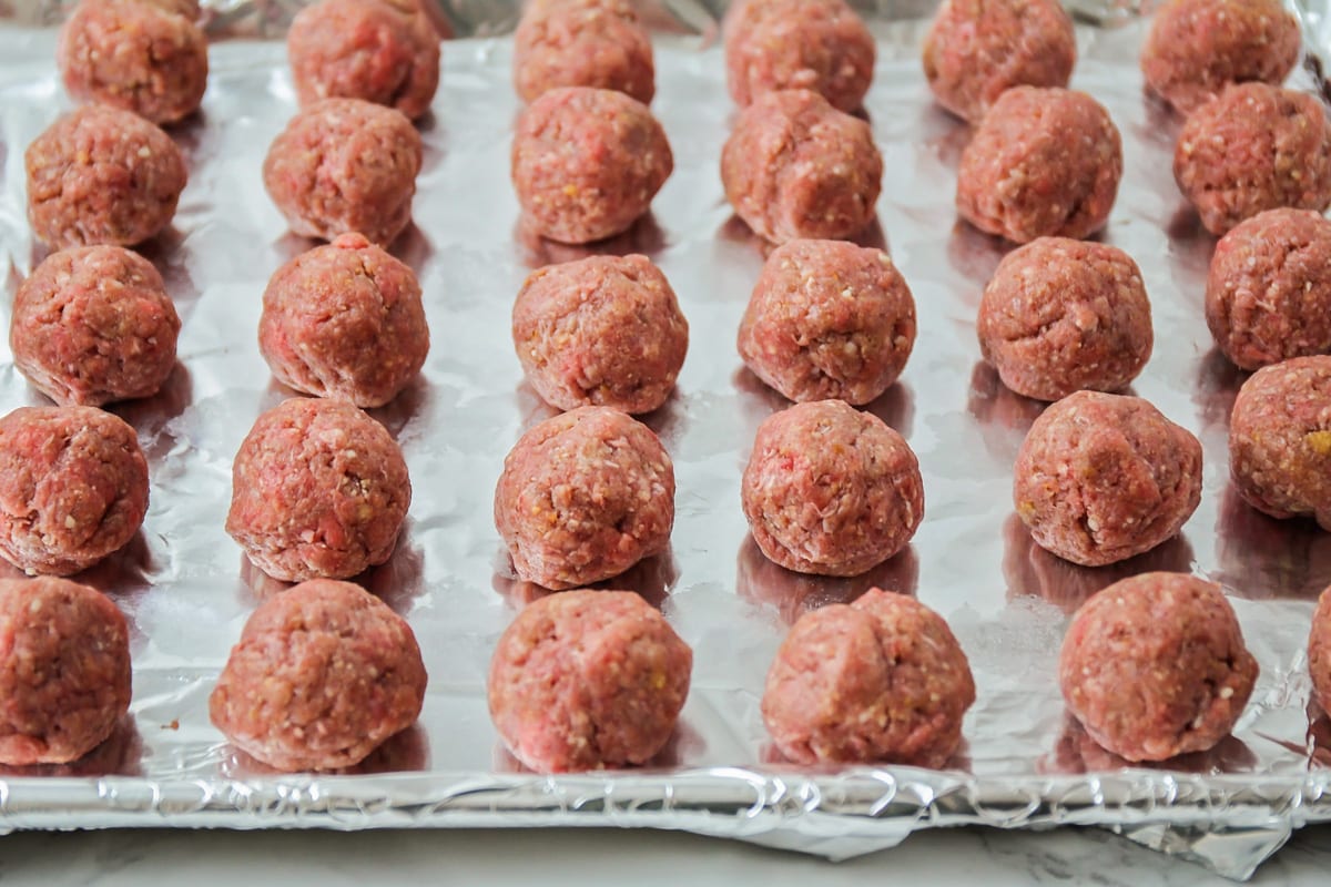 Meatballs shaped and placed on foil-lined baking sheet.