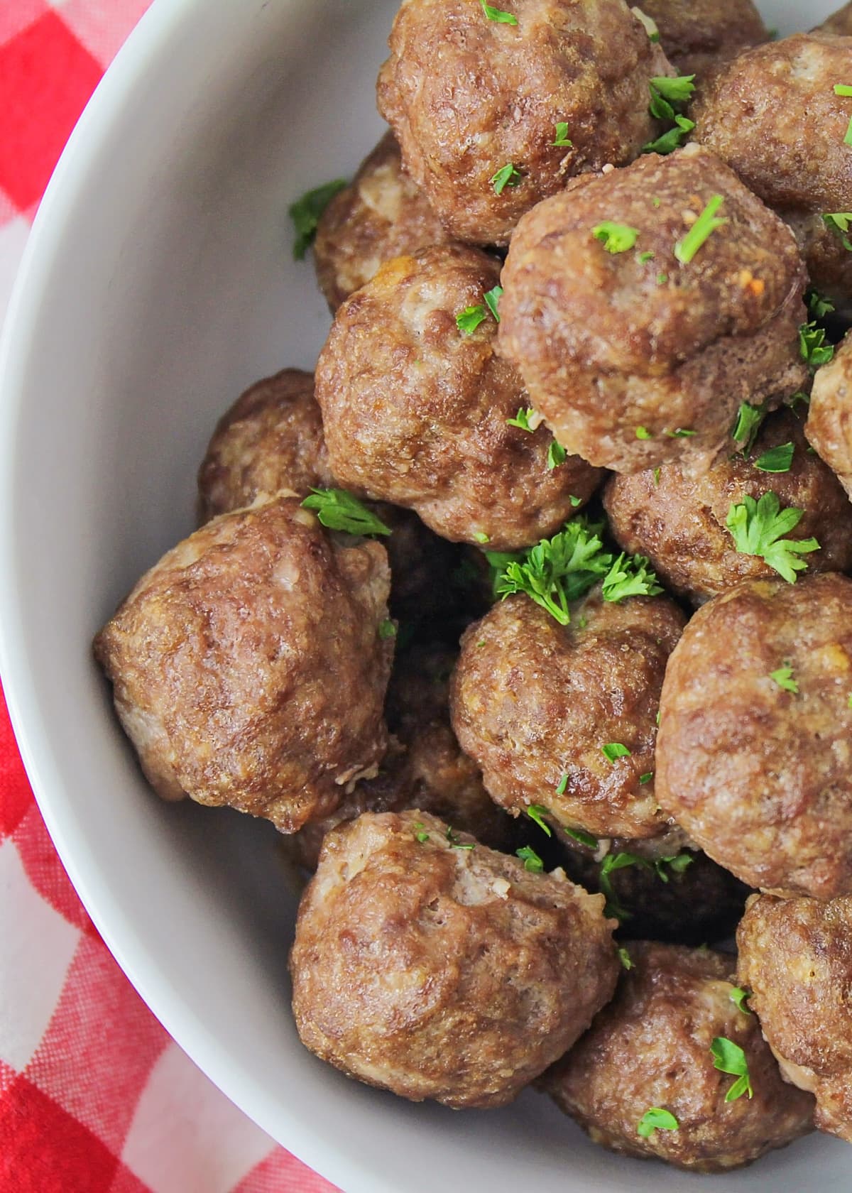 Easy meatball recipe in white bowl topped with fresh herbs.
