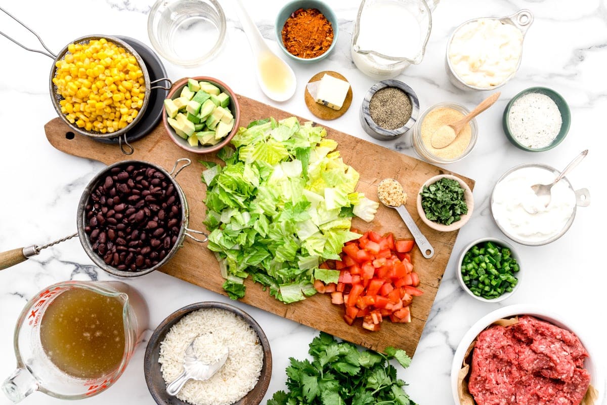 Meat, cheese, veggies, and other taco ingredients on a kitchen counter.