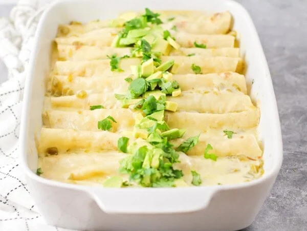 White chicken enchiladas in white casserole dish.