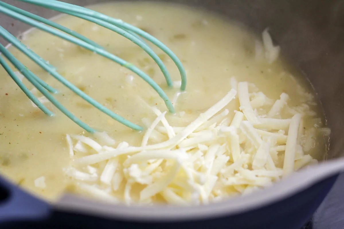 White queso being made in pot for white chicken enchilada recipe.