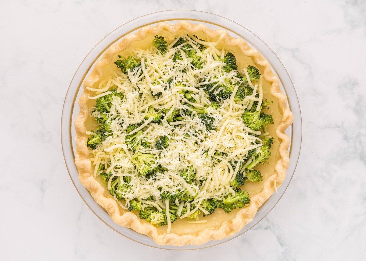 A pie crust filled with broccoli and topped with cheese.