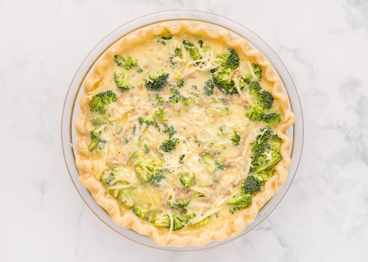 An egg mixture poured on top of broccoli and cheese in a pie crust.