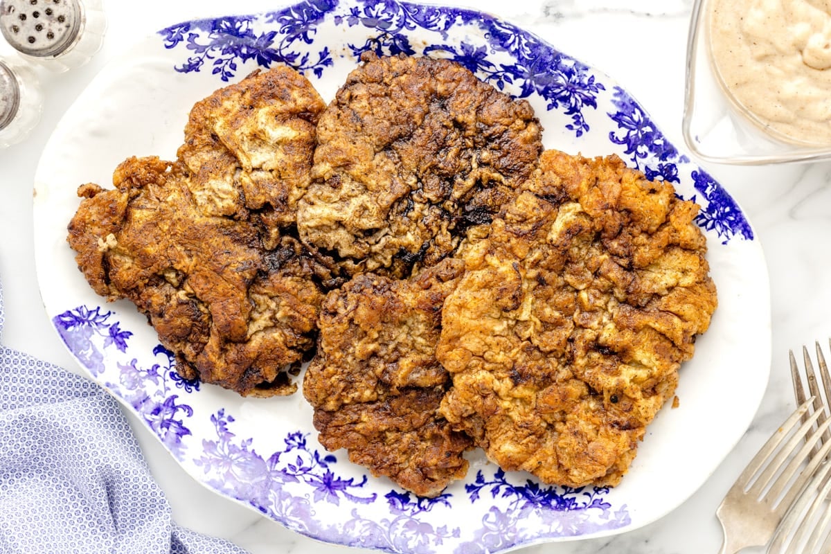 Several fried steaks on a blue and white plate.