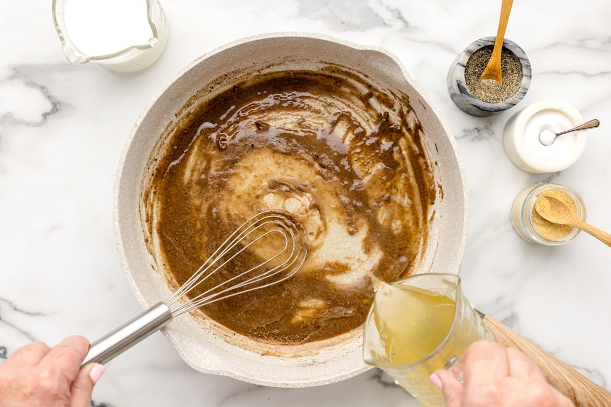 Adding liquid to a gravy mix on the stove.