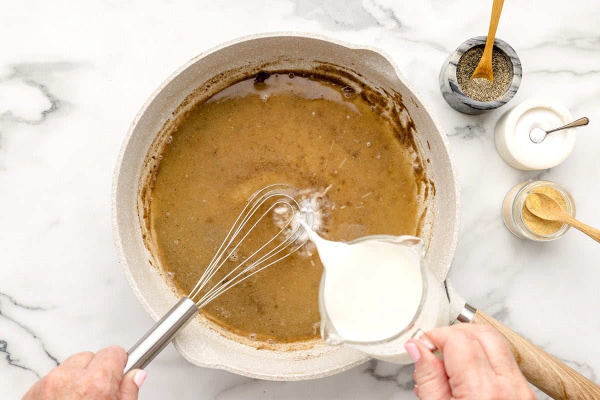 Adding milk to savory mixture in a pan on the stove.