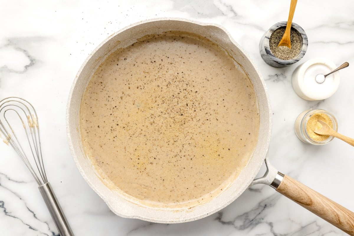 Gravy sprinkled with pepper in a pan on the counter.