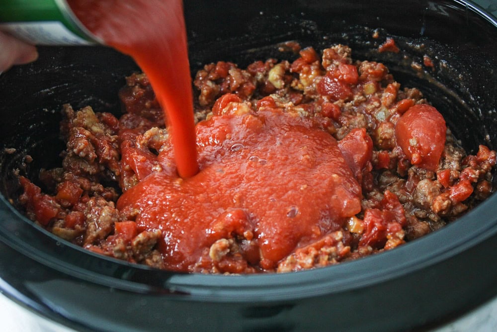 Meat and sauce being poured into crock pot.