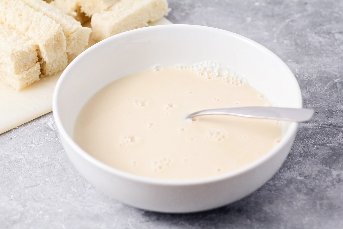 Eggs, milk and vanilla mixed together in a bowl.