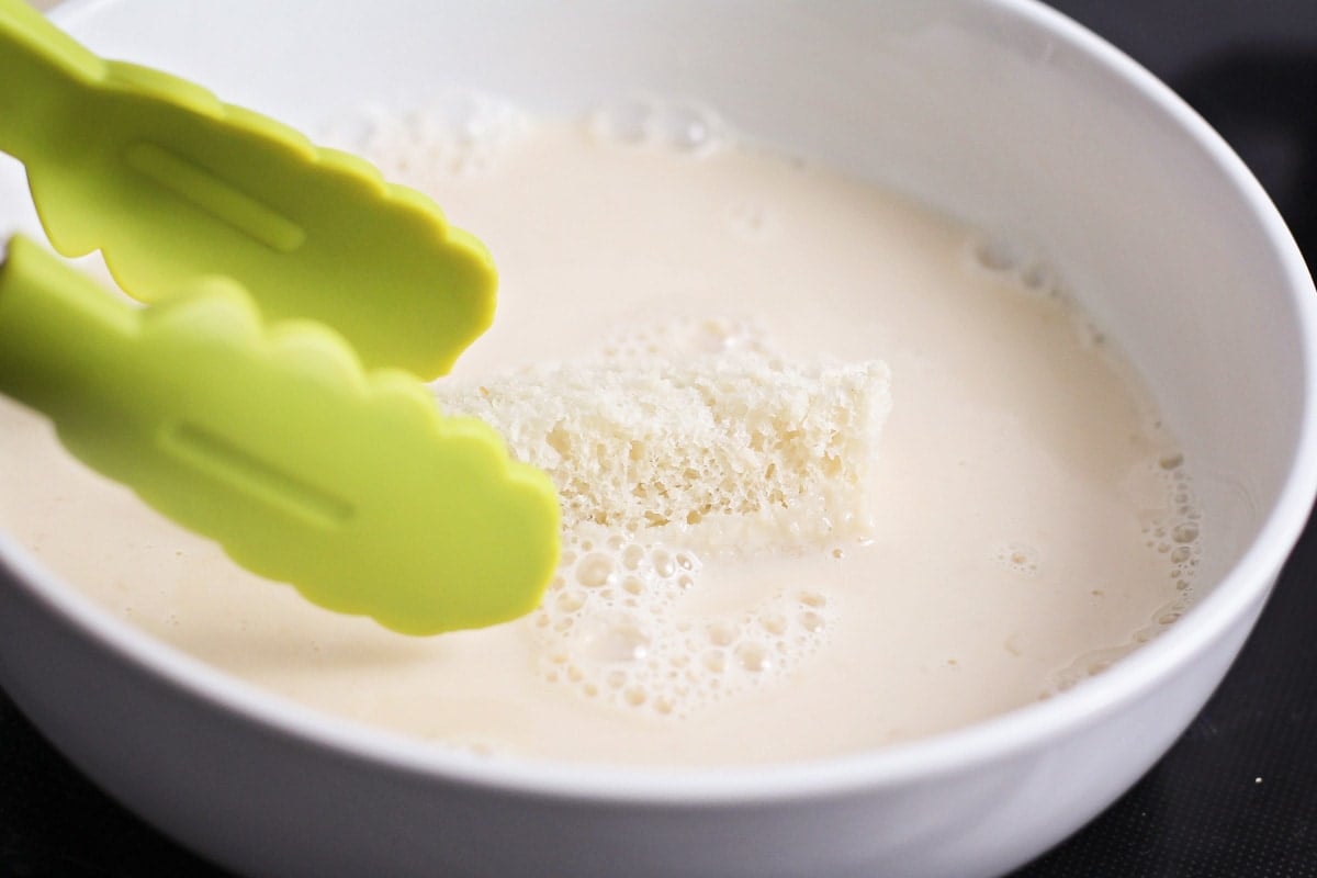 Dipping bread sticks into a bowl of milk and egg mixture.