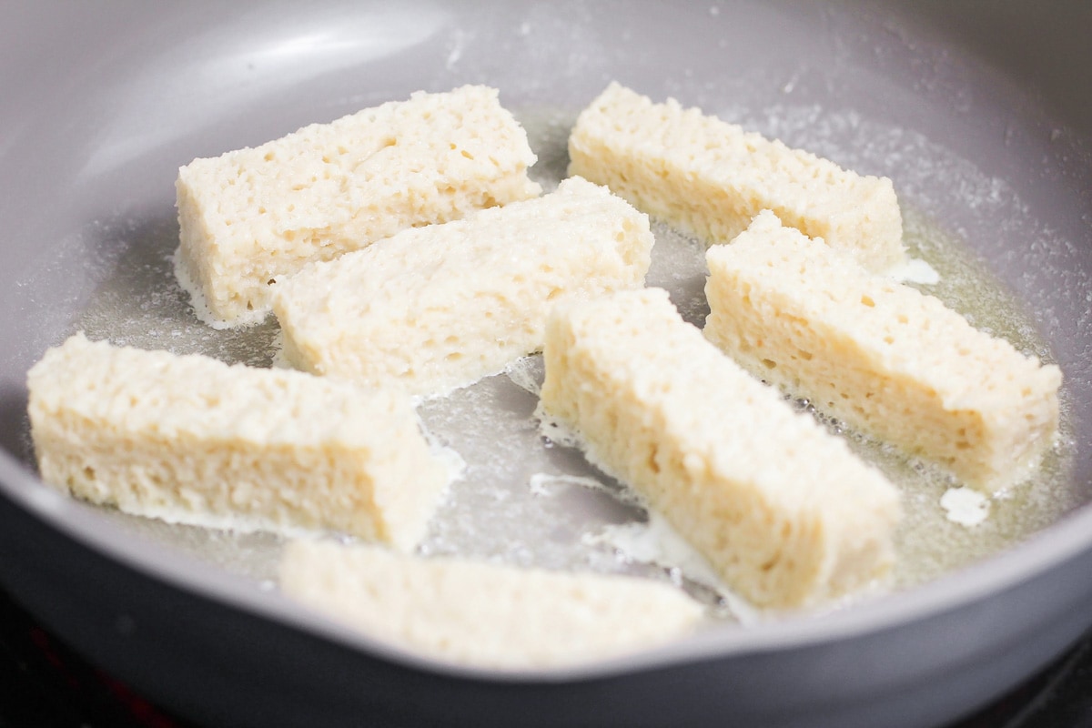 French toast sticks cooking in skillet.