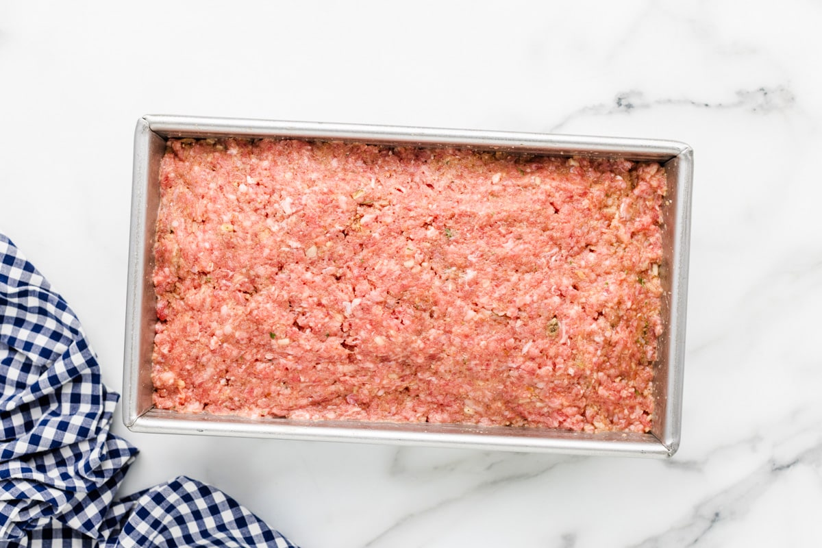 Ground beef mixture pressed into a loaf pan.