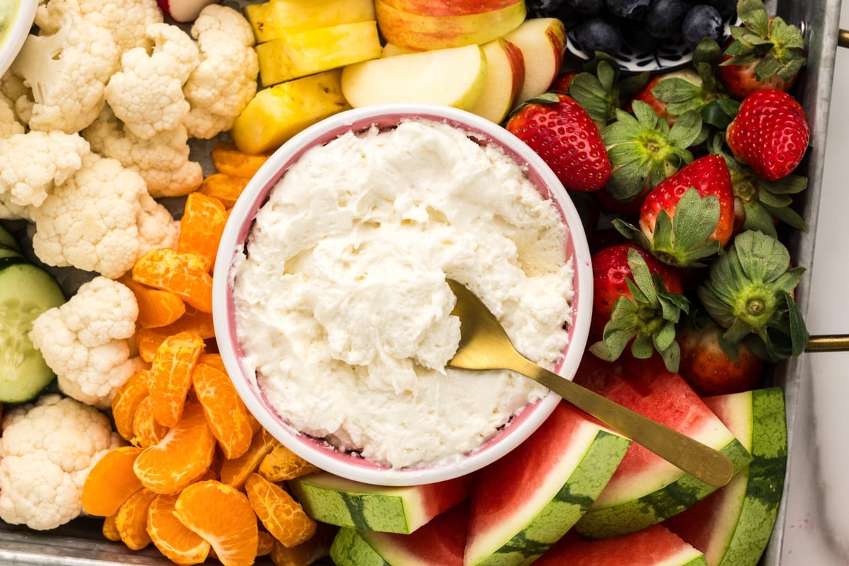 Yogurt fruit dip served in a bowl alongside fresh fruit.