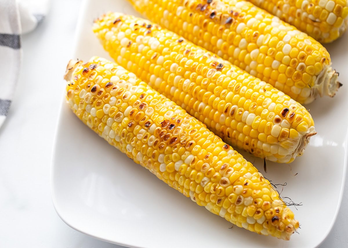 Grilled corn on the cob on white plate.