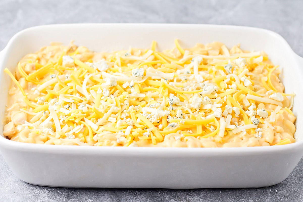 Adding pasta and cheese to a baking dish.