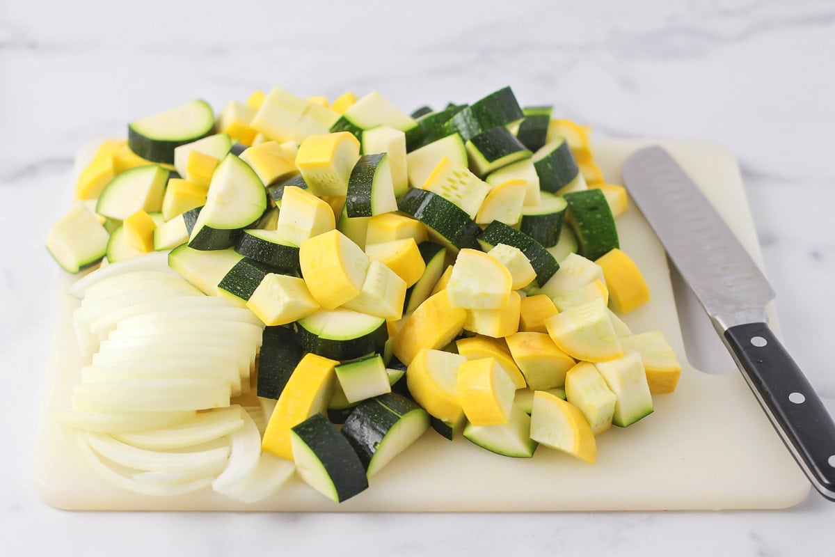 Diced squash and onions on a cutting board.