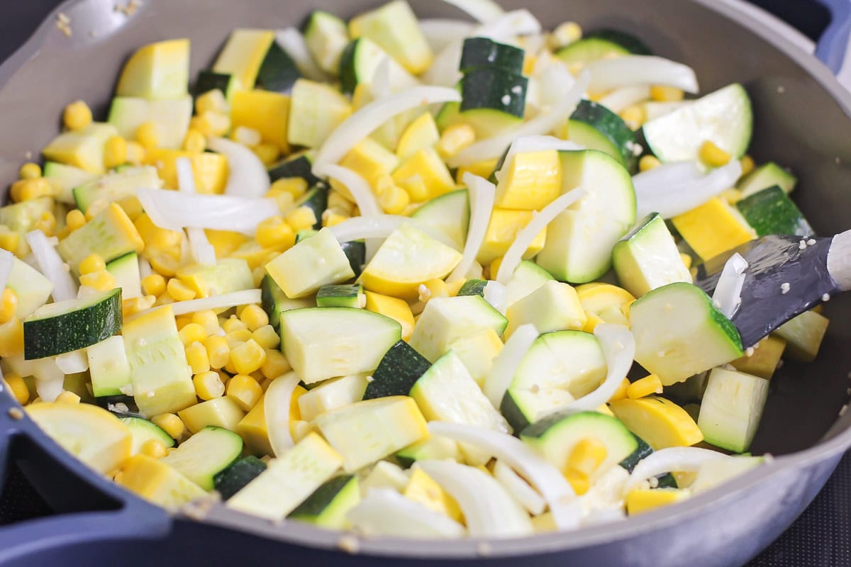 Adding veggies to the skillet of oil and garlic.