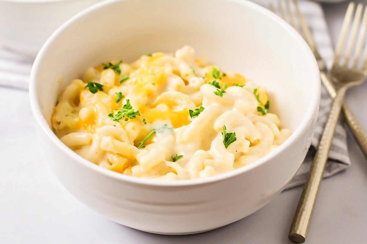 A white bowl of Chick Fil A mac and cheese topped with fresh herbs.